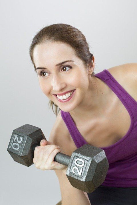 a girl with a dumbbell is doing an exercise to lose weight